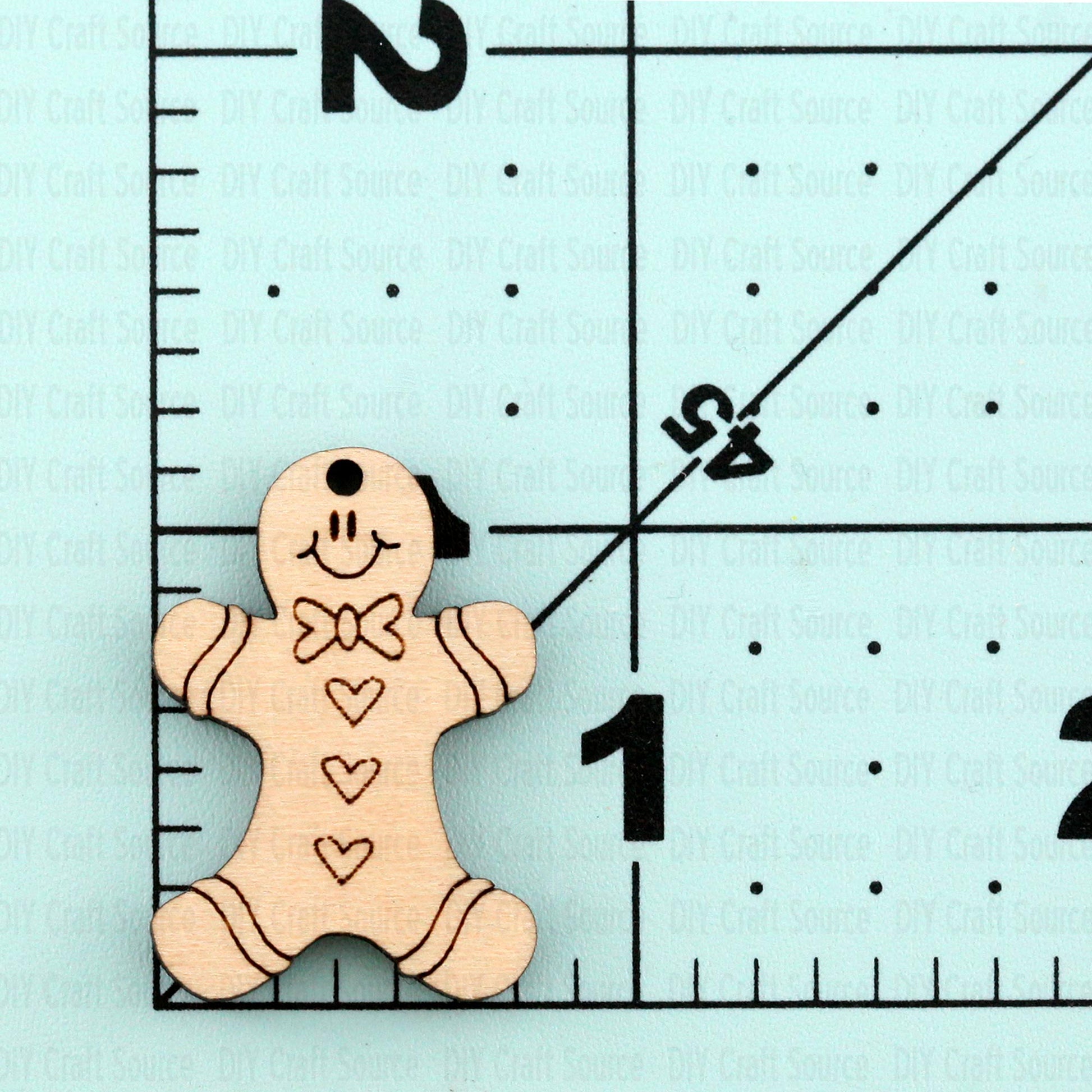 Wooden gingerbread man earrings on a light blue background with measurement markings that are ready to paint.
