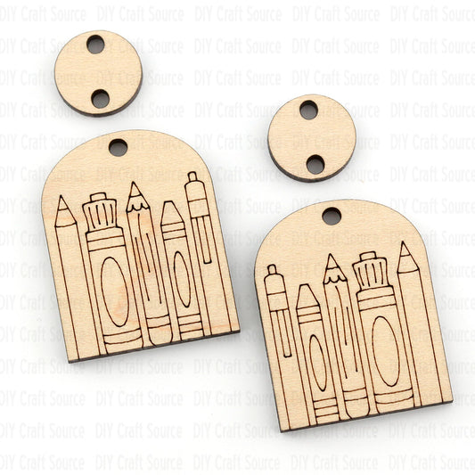 Wooden earrings with pencil and crayon designs on a white background that are ready to paint